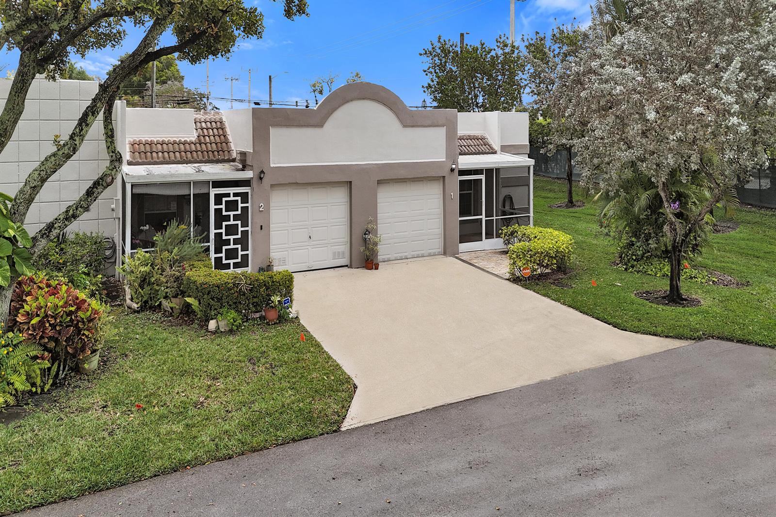An exterior view of a duplex with two garage doors and screened-in entryways — 9005 Flynn Circle # 1, Boca Raton FL 33496, BOCA RATON, FL