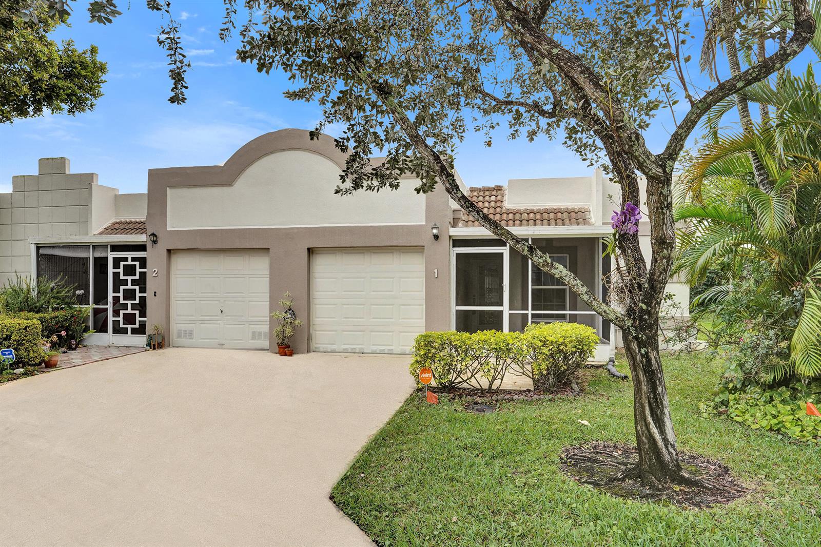 A single-story duplex with two garage doors, a screened-in porch, and a paved driveway — 9005 Flynn Circle # 1, Boca Raton FL 33496, BOCA RATON, FL