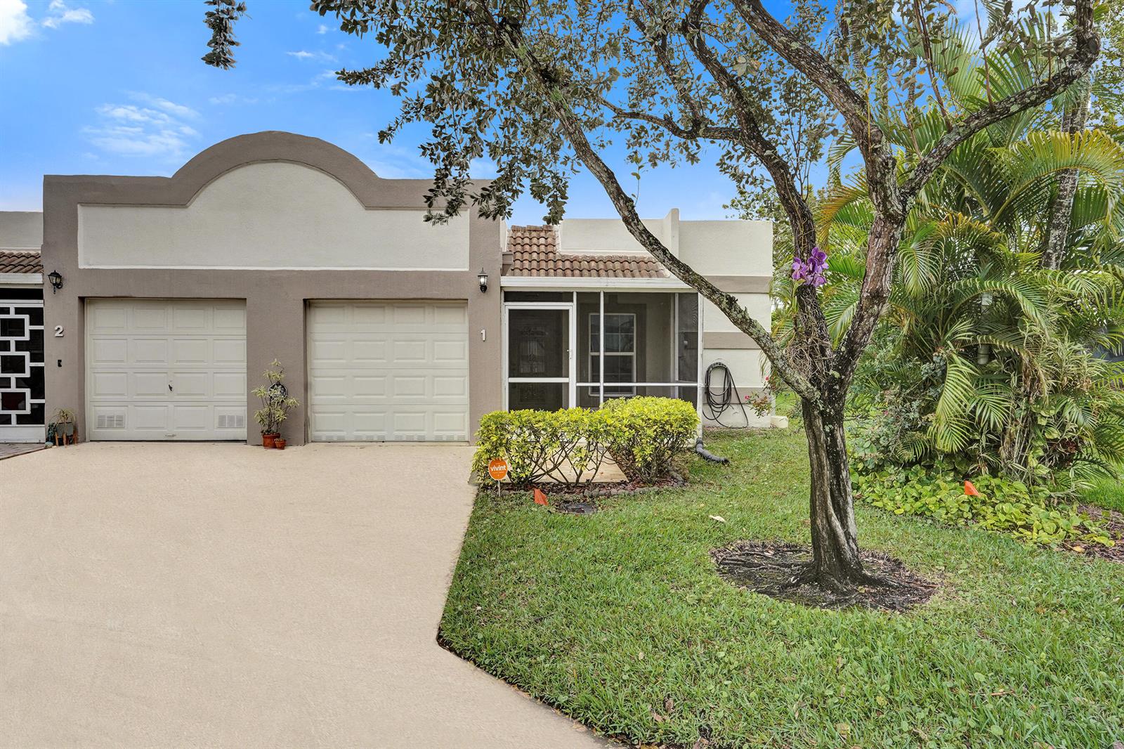 A single-story townhouse with two garage doors, a screened-in entryway, and a front lawn — 9005 Flynn Circle # 1, Boca Raton FL 33496, BOCA RATON, FL