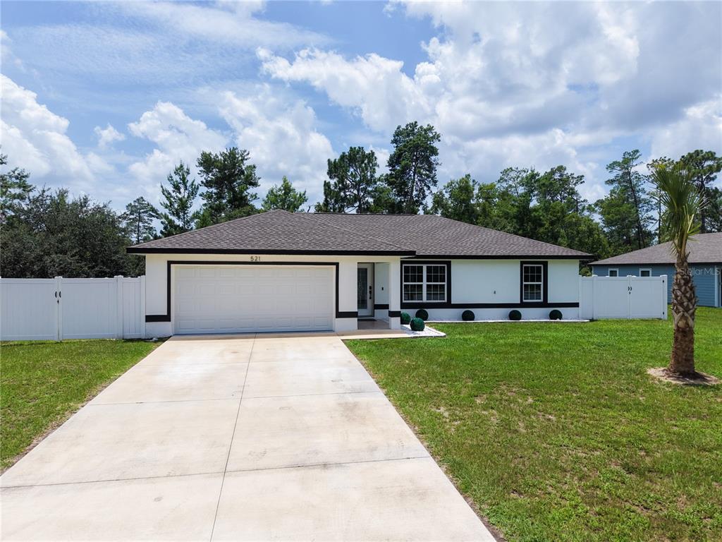 A single-story house with a white exterior, black trim, and a concrete driveway — 521 MARION OAKS BOULEVARD, OCALA, FL