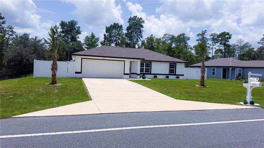 A white single-story house with a two-car garage and a concrete driveway — 521 MARION OAKS BOULEVARD, OCALA, FL
