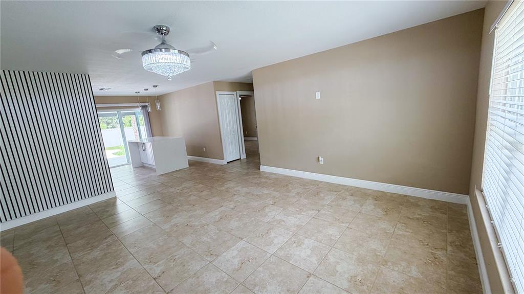 An open-concept living area features tile flooring, a crystal ceiling fan, and a striped accent wall — 521 MARION OAKS BOULEVARD, OCALA, FL