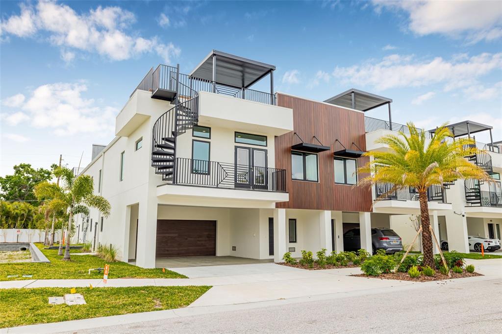 A modern multi-story townhouse exterior features a spiral staircase, rooftop terrace, and wood-paneled accents — 8631 5TH STREET NORTH, ST PETERSBURG, FL