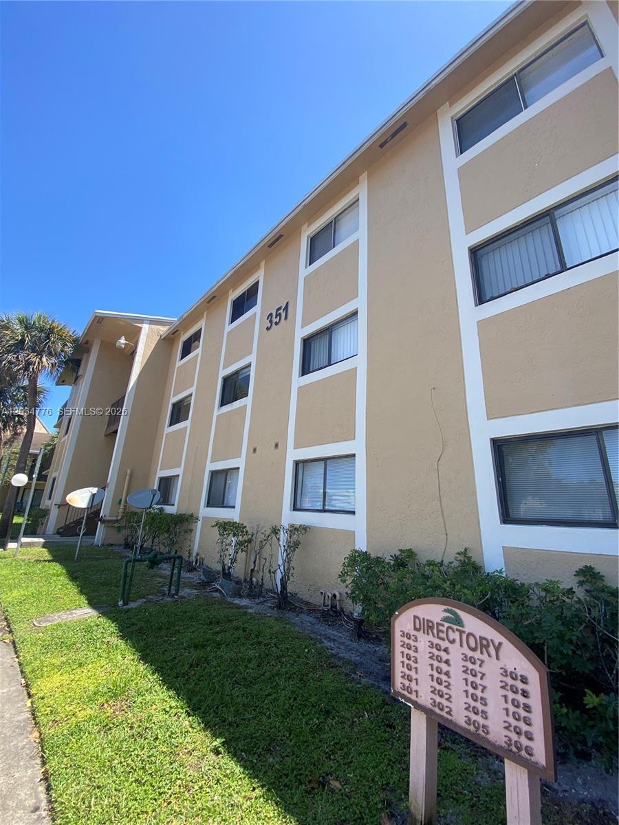 The exterior of a multi-story apartment building features a directory sign in the foreground — PEMBROKE PINES, FL