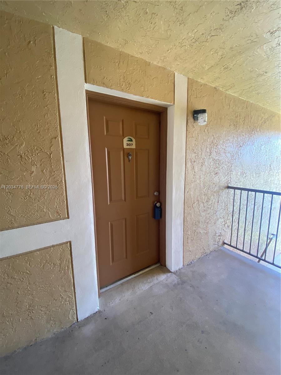 A brown apartment door labeled 307 is set in a textured beige exterior wall — PEMBROKE PINES, FL