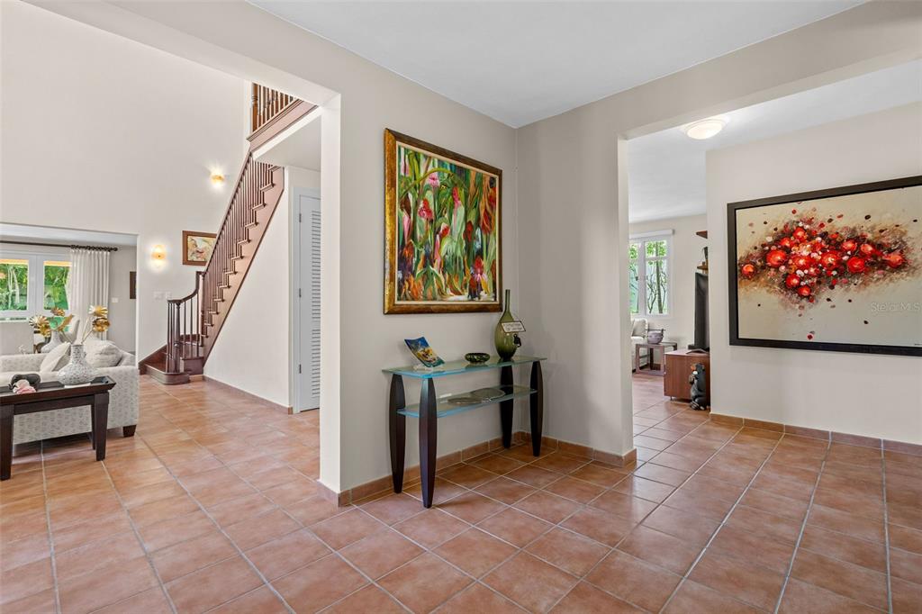 A tiled entryway features a staircase, a glass console table, and two large wall paintings — 368 100 DORADO BEACH DRIVE, DORADO, PR