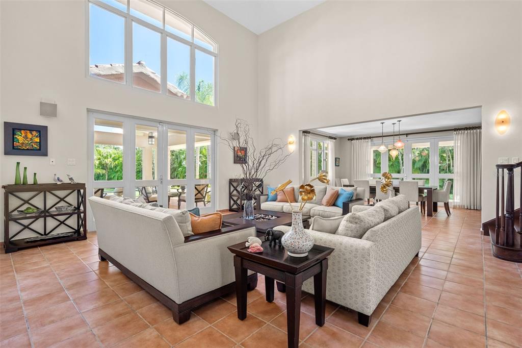 A high-ceilinged living room features tile floors, neutral furniture, and large glass doors to a patio — 368 100 DORADO BEACH DRIVE, DORADO, PR