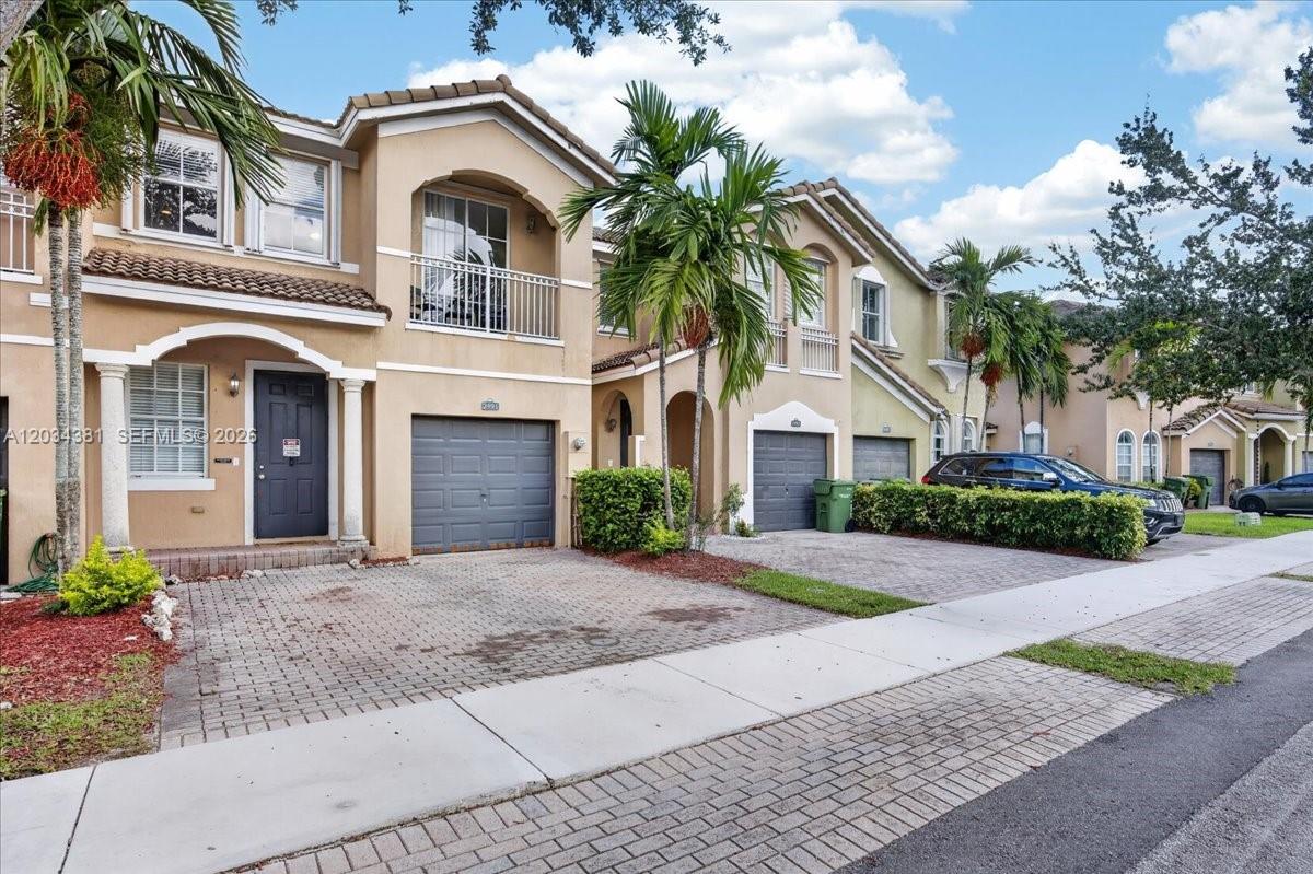 A two-story townhouse with a beige stucco exterior, a garage, and a paved driveway — 2491 SE 13th Ct, Homestead FL 33035, HOMESTEAD, FL