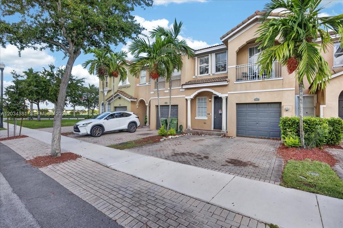 A two-story townhouse with a paved driveway, a garage, and a white car parked outside — 2491 SE 13th Ct, Homestead FL 33035, HOMESTEAD, FL