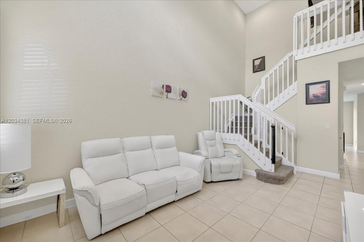 A living room features a white sofa, a matching recliner, and a staircase with railings — 2491 SE 13th Ct, Homestead FL 33035, HOMESTEAD, FL