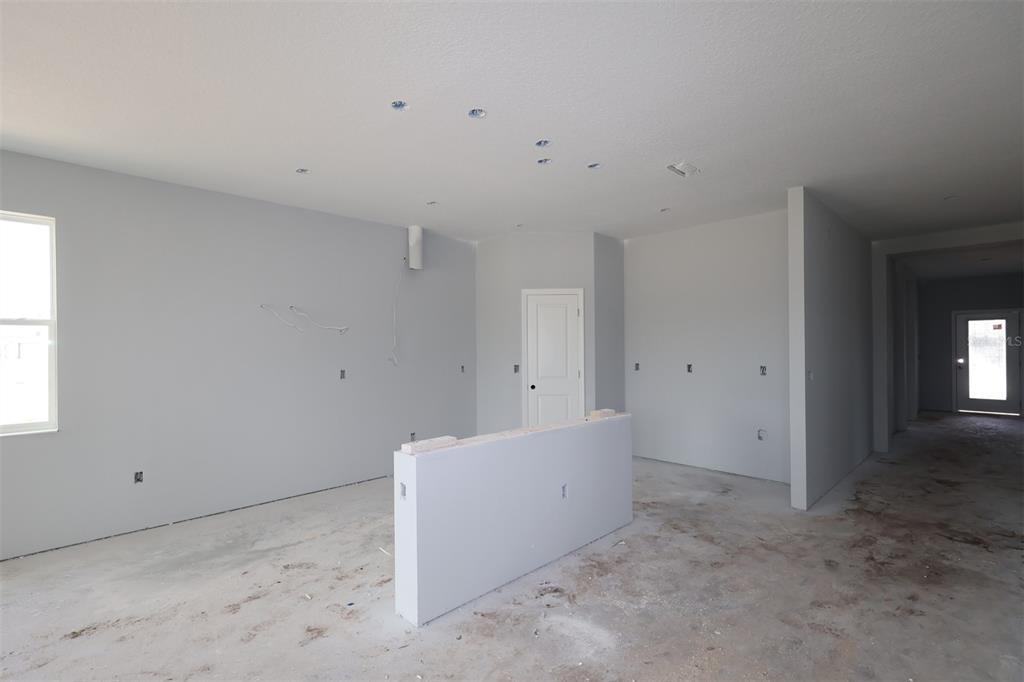 An unfinished kitchen features white cabinetry, a center island with blue protective film, and tile — 5248 HIGH LINE DRIVE, ST CLOUD, FL