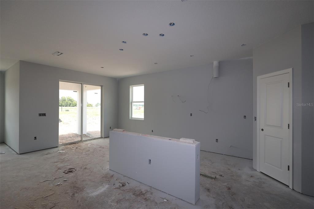 A kitchen under construction features a center island, gray cabinets, and a tiled backsplash — 5248 HIGH LINE DRIVE, ST CLOUD, FL