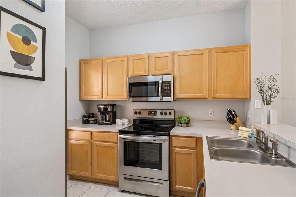 A kitchen features light wood cabinets, stainless steel appliances, and gray countertops — 8498 CRYSTAL COVE LOOP, KISSIMMEE, FL