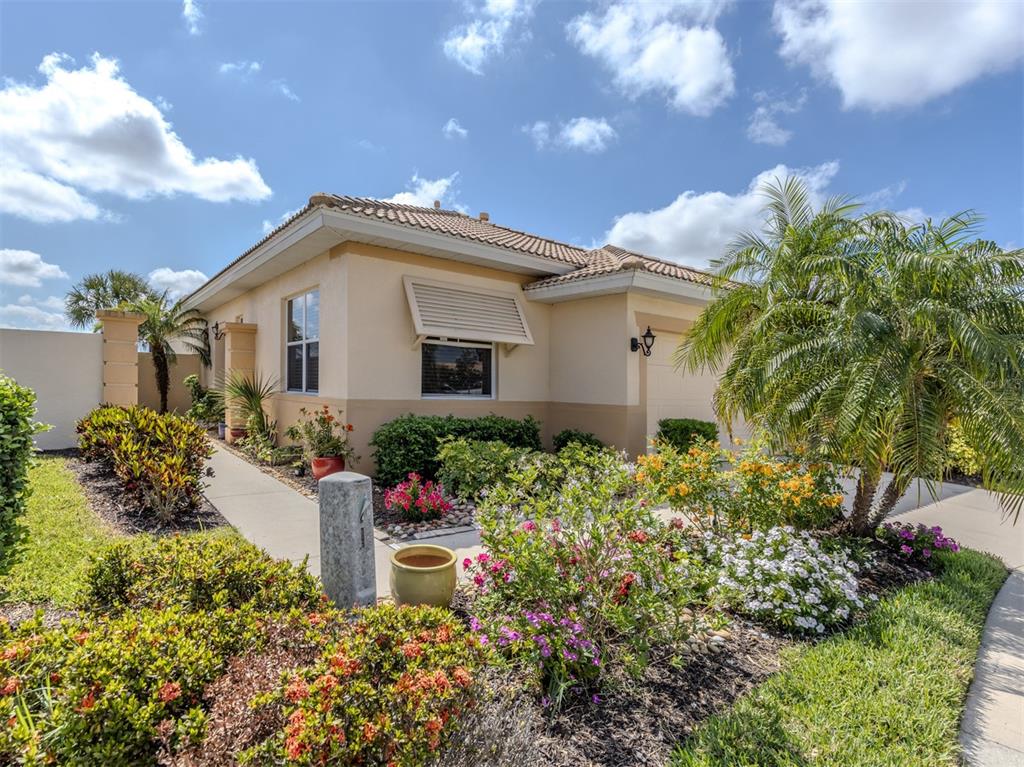 A single-story house with a beige stucco exterior, a tiled roof, and a landscaped front yard — 101 MESTRE PLACE, NORTH VENICE, FL