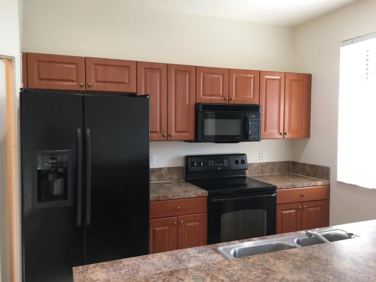 A kitchen features wood cabinets, black appliances, and brown laminate countertops — 1213 Abaco Lane, West Palm Beach FL 33404, WEST PALM BEACH, FL