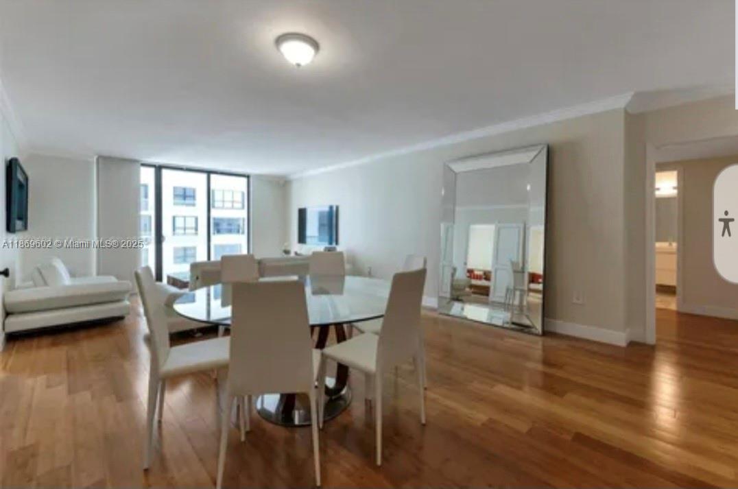 A dining area features a glass table with white chairs, hardwood floors, and a large mirror — 9801 Collins Ave # 10T, Bal Harbour FL 33154, BAL HARBOUR, FL