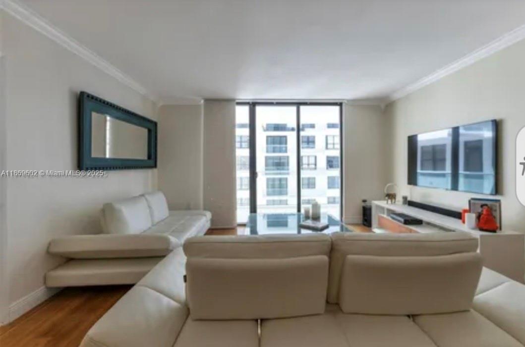 A living room features white leather sofas, a wall-mounted television, and a large window — 9801 Collins Ave # 10T, Bal Harbour FL 33154, BAL HARBOUR, FL