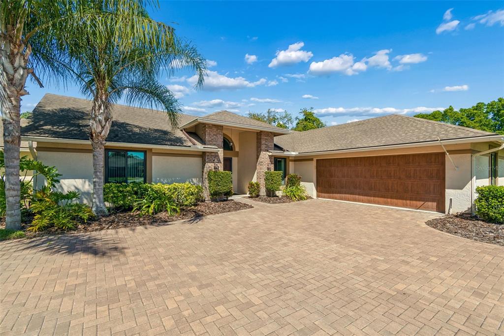 A single-story house with a stone-accented entryway, a two-car garage, and a paved driveway — 8723 ASHBURY DRIVE, HUDSON, FL