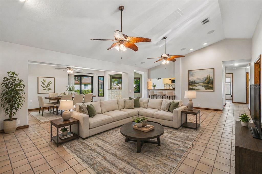 A spacious living room with tile floors, a sectional sofa, and two ceiling fans — 8723 ASHBURY DRIVE, HUDSON, FL