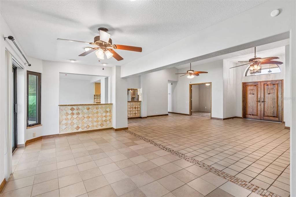 An open-concept living area features tiled floors, a tiled breakfast bar, and two ceiling fans — 8723 ASHBURY DRIVE, HUDSON, FL