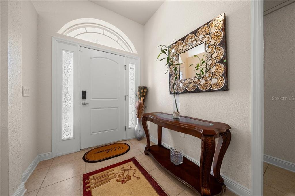 An entryway features a white front door with sidelights, tile flooring, and a decorative mirror — 9870 SW 55TH AVENUE ROAD, OCALA, FL