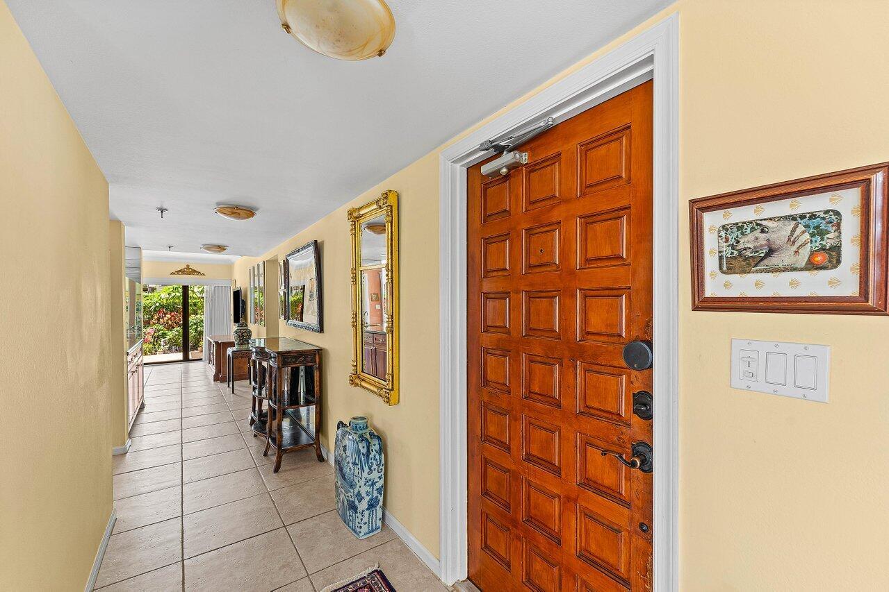 A hallway with tile flooring leads to a glass door opening onto a patio — 372 Golfview Road # 101, North Palm Beach FL 33408, NORTH PALM BEACH, FL