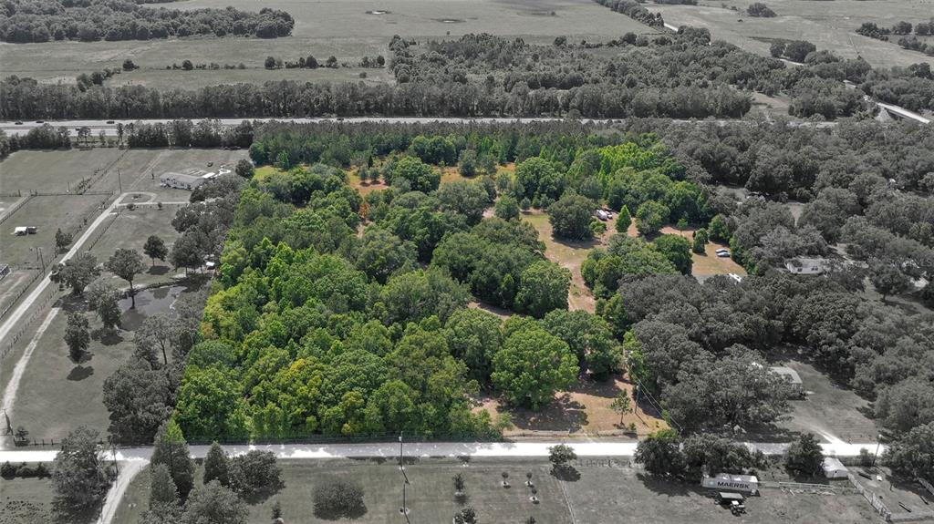 An aerial view shows a large, wooded lot bordered by a road and neighboring properties — 14815 SHERROD CROFT LANE, DADE CITY, FL