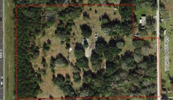 An aerial view shows a wooded lot outlined in red next to a paved road — 14815 SHERROD CROFT LANE, DADE CITY, FL