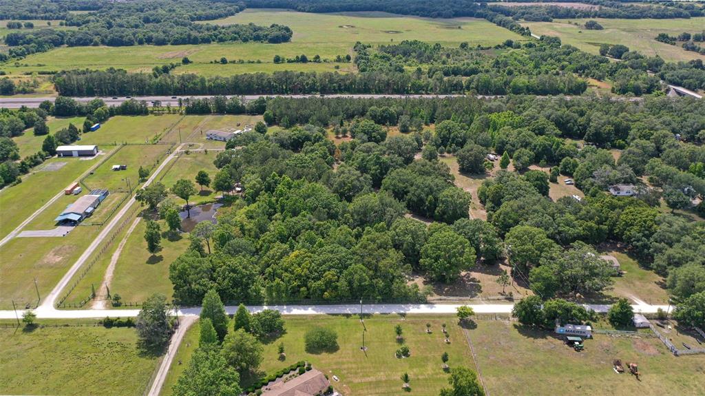 An aerial view shows a large, wooded rural property with a pond and nearby highway — 14815 SHERROD CROFT LANE, DADE CITY, FL