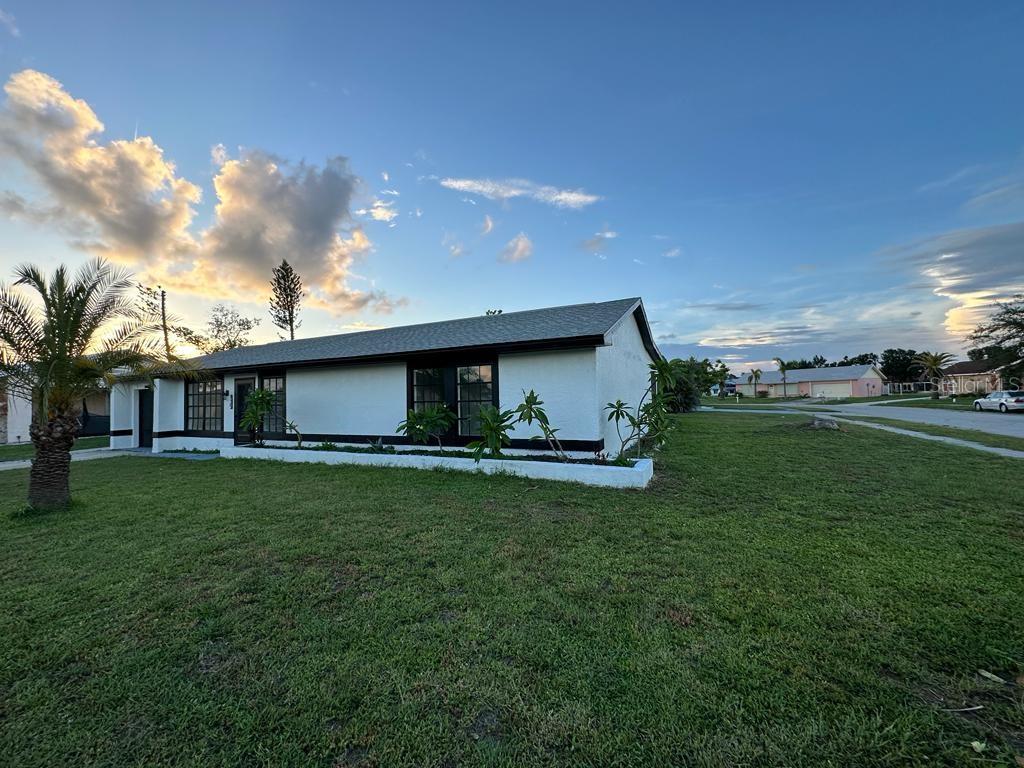 A white single-story house with a dark roof and trim sits on a grassy lot — 13556 ROMFORD AVENUE, PORT CHARLOTTE, FL