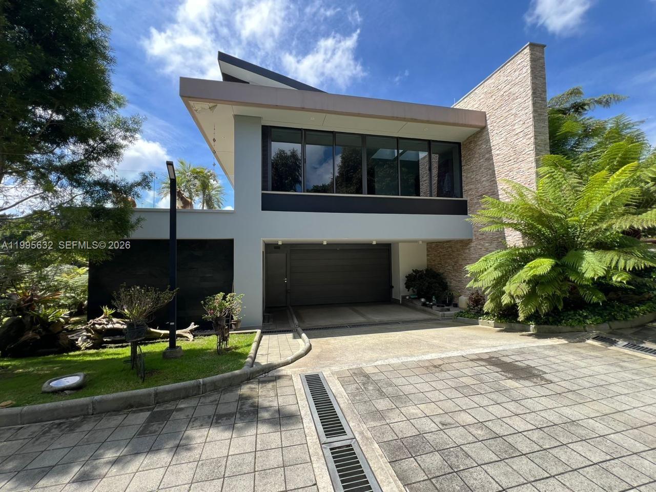 A modern two-story house features a stone facade, a garage, and large upper-level windows — Alto de Las Palmas Km 17, vía La Acuarela, FL