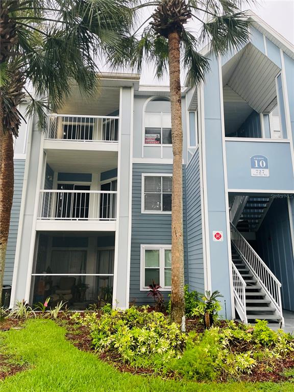 A three-story blue apartment building features balconies, an exterior staircase, and palm trees — 727 SUGAR BAY WAY UNIT 303, LAKE MARY, FL