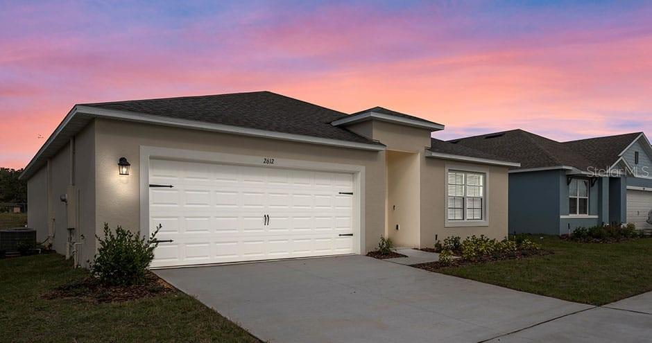 A single-story house with a beige exterior, a two-car garage, and a concrete driveway — 2429 MAIDENS BLUFF AVENUE UNIT Hayden, DAVENPORT, FL