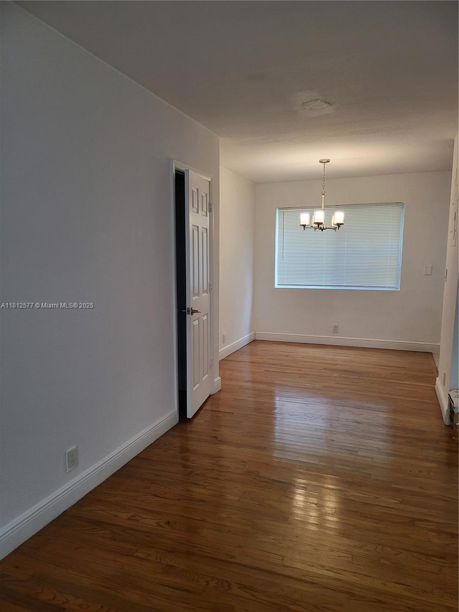 An empty dining room features hardwood floors, a white door, and a hanging light fixture — 340 84th St # 2, Miami Beach FL 33141, MIAMI BEACH, FL