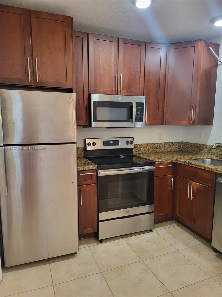 A kitchen features dark wood cabinets, stainless steel appliances, and granite countertops — 340 84th St # 2, Miami Beach FL 33141, MIAMI BEACH, FL