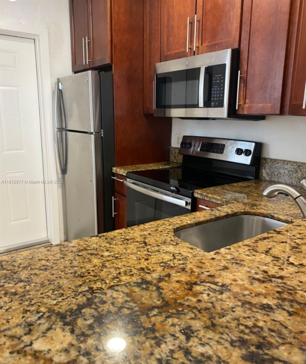 A kitchen features dark wood cabinets, stainless steel appliances, and speckled granite countertops — 340 84th St # 2, Miami Beach FL 33141, MIAMI BEACH, FL