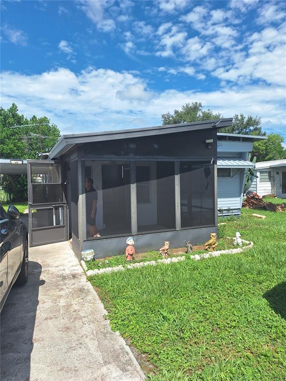 A mobile home features a screened-in front porch with lawn ornaments and a concrete driveway — 6349 NEW YORK STREET, ZEPHYRHILLS, FL