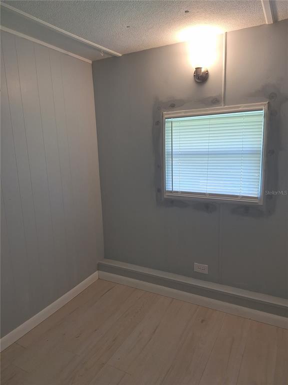 A small room with light-colored wood flooring, gray walls, and a single window with blinds — 6349 NEW YORK STREET, ZEPHYRHILLS, FL