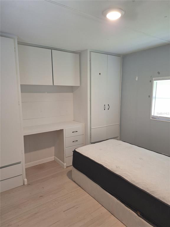 A bedroom features a built-in desk, white cabinetry, light wood flooring, and a single bed — 6349 NEW YORK STREET, ZEPHYRHILLS, FL