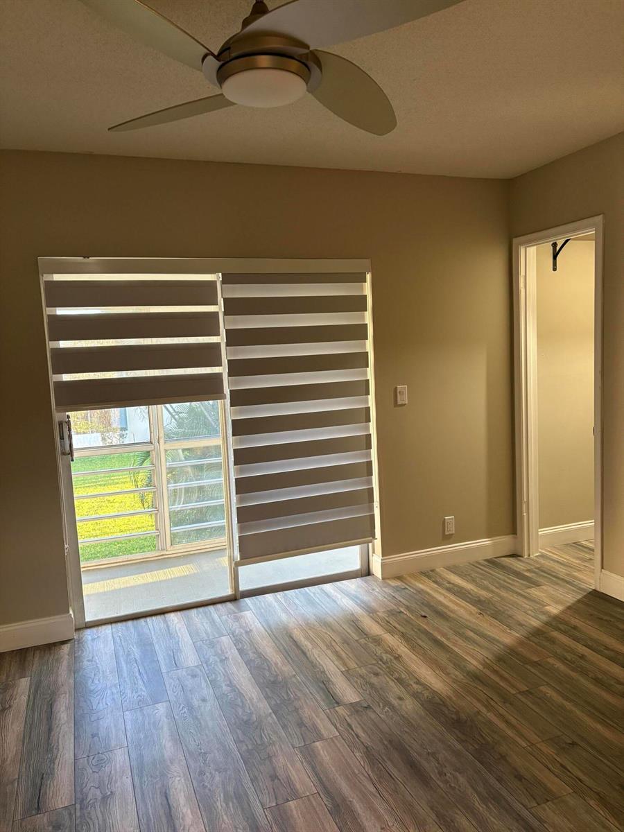 A room with wood-look flooring, a ceiling fan, and sliding glass doors with zebra blinds — 111 E Waltham, West Palm Beach FL 33417, WEST PALM BEACH, FL