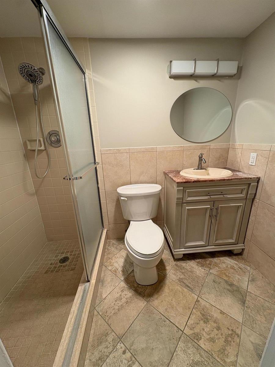 A bathroom features a glass-enclosed shower, a toilet, and a vanity with a stone countertop — 111 E Waltham, West Palm Beach FL 33417, WEST PALM BEACH, FL