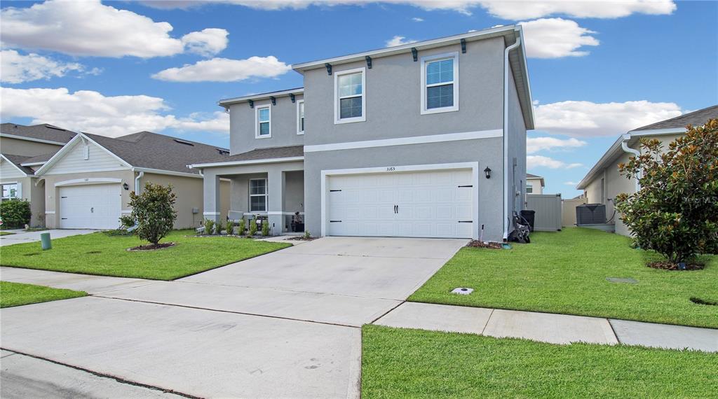 A two-story suburban house with a gray stucco exterior, a two-car garage, and a lawn — 3165 EASTGROVE TERRACE, SANFORD, FL