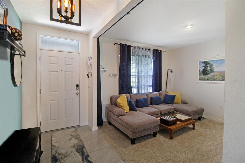 A living room with a sectional sofa, coffee table, and an adjacent entryway with tile — 3165 EASTGROVE TERRACE, SANFORD, FL