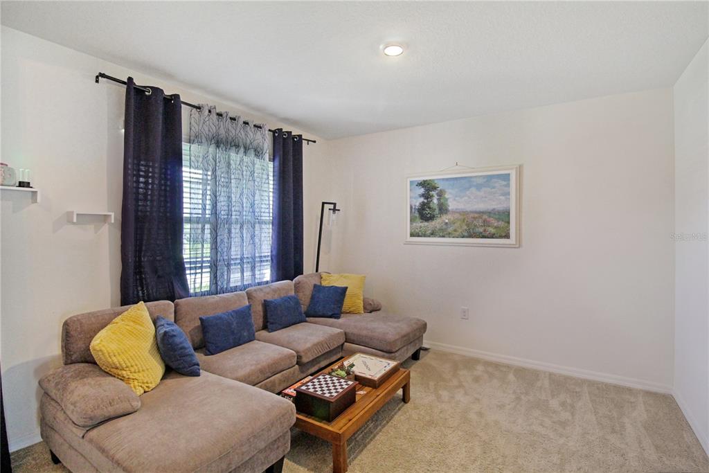 A living room features a beige sectional sofa, a wooden coffee table, and wall art — 3165 EASTGROVE TERRACE, SANFORD, FL