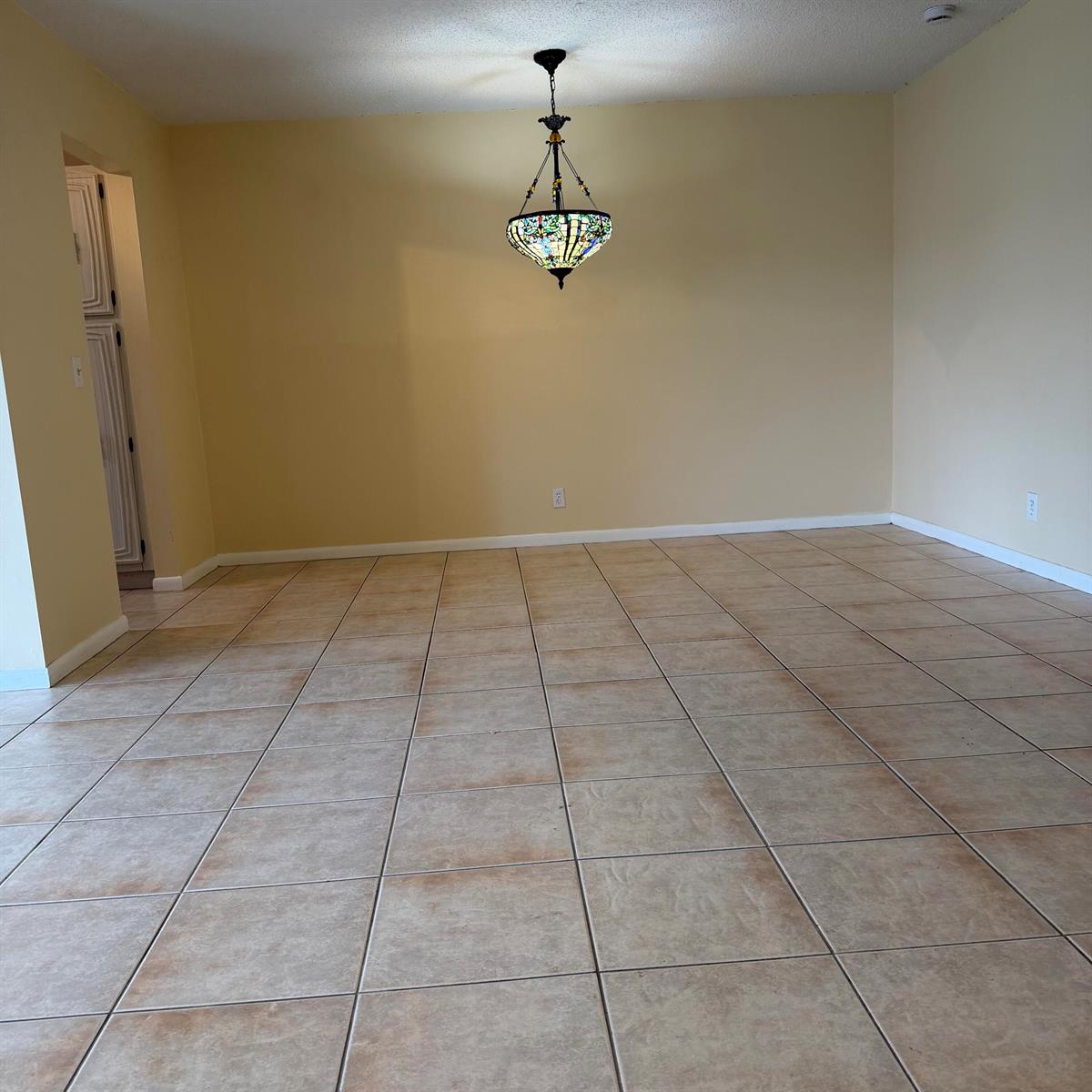 An empty dining room features beige walls, tan tile flooring, and a stained-glass chandelier — 707 High Point Boulevard N Unit C, Delray Beach FL 33445, DELRAY BEACH, FL