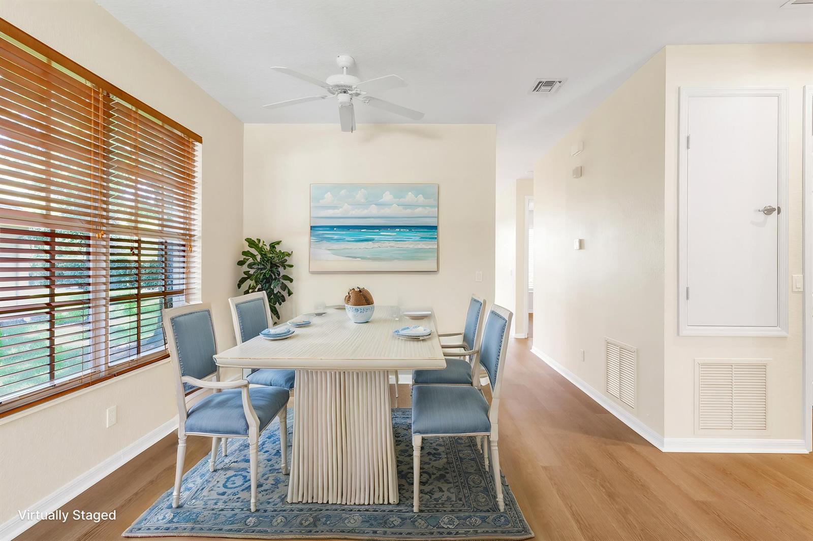A dining room with a white table, blue chairs, a patterned rug, and wood flooring — 9975 E Villa Circle, Vero Beach FL 32966, VERO BEACH, FL