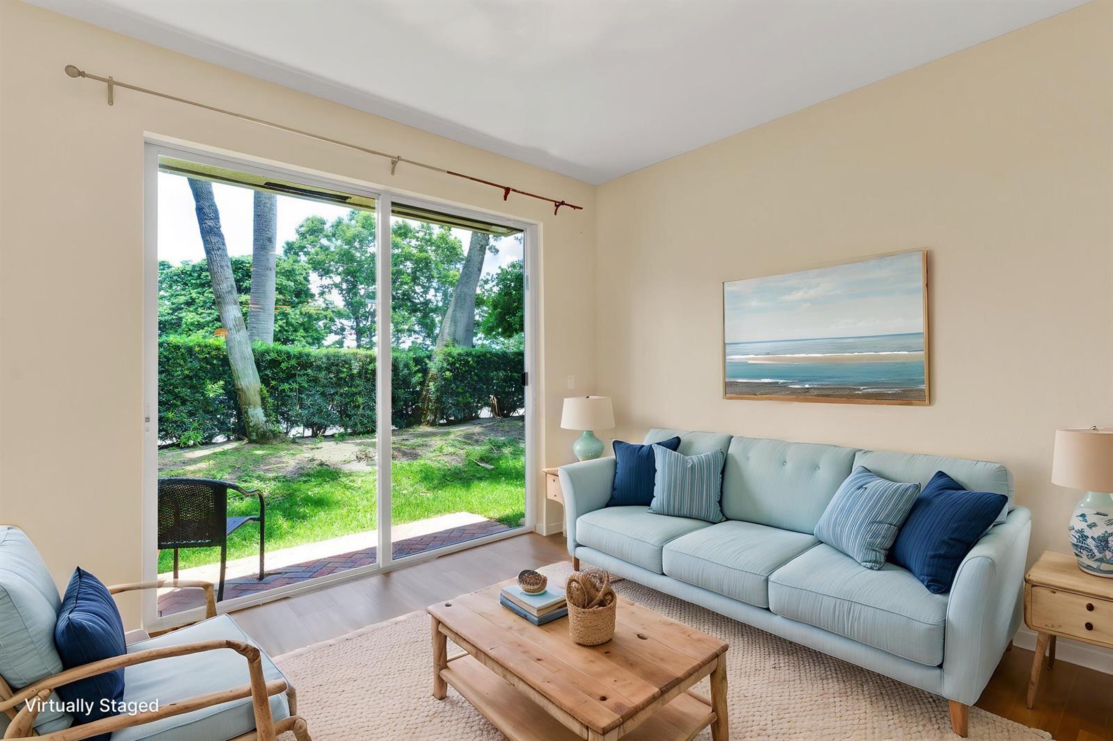 A living room features a light blue sofa, wooden coffee table, and sliding glass doors — 9975 E Villa Circle, Vero Beach FL 32966, VERO BEACH, FL