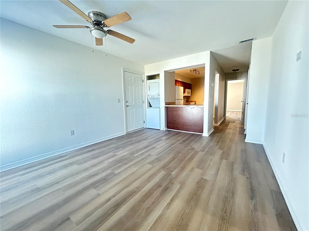 An interior view shows a living area with wood-look flooring, a ceiling fan, and kitchen — 705 HAVEN PLACE UNIT 705, TARPON SPRINGS, FL