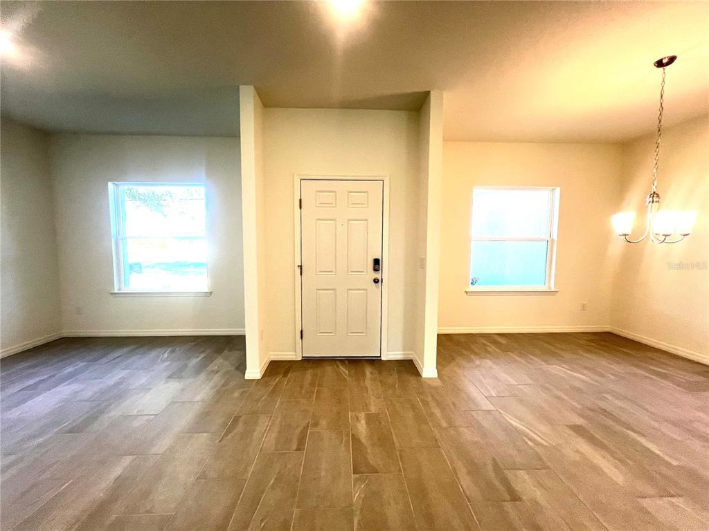 An interior view shows a room with wood-look tile flooring, a front door, and windows — 4 LYNBROOK DRIVE, PALM COAST, FL