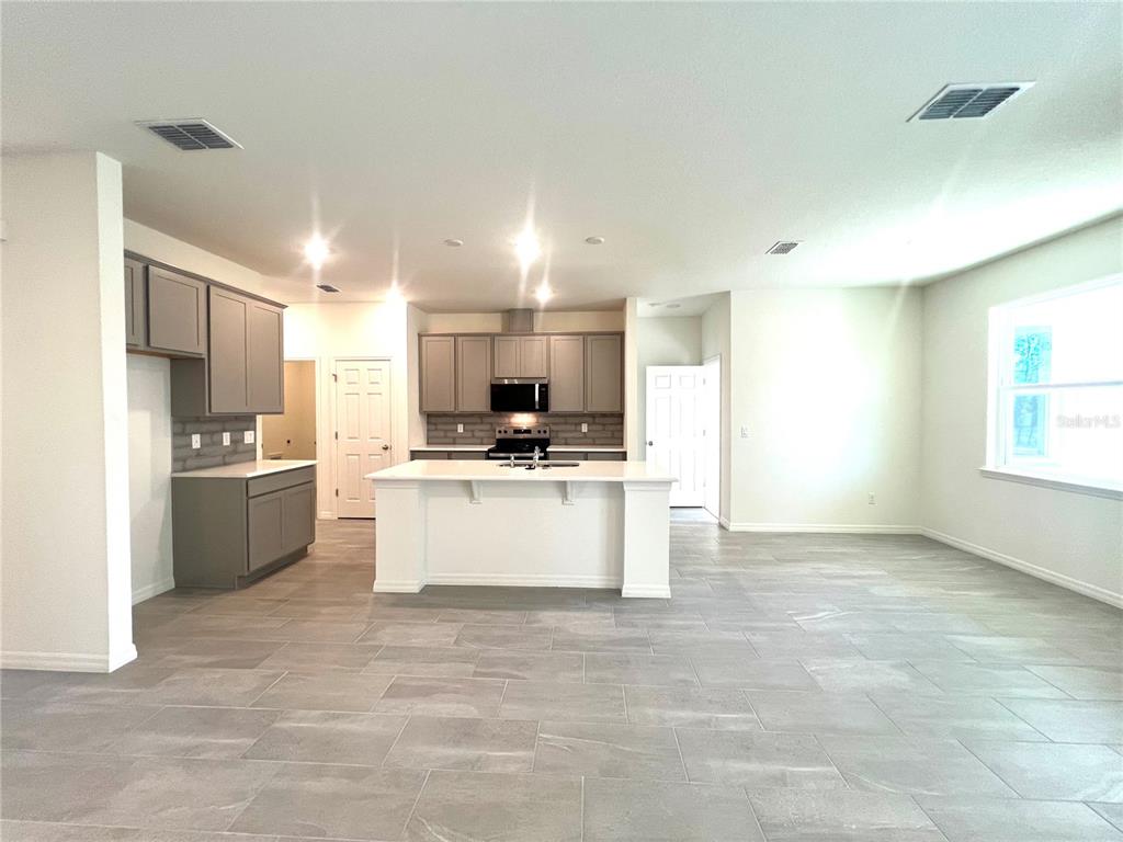 A kitchen features gray cabinets, a white island, and light-colored tile flooring — 4 LYNBROOK DRIVE, PALM COAST, FL
